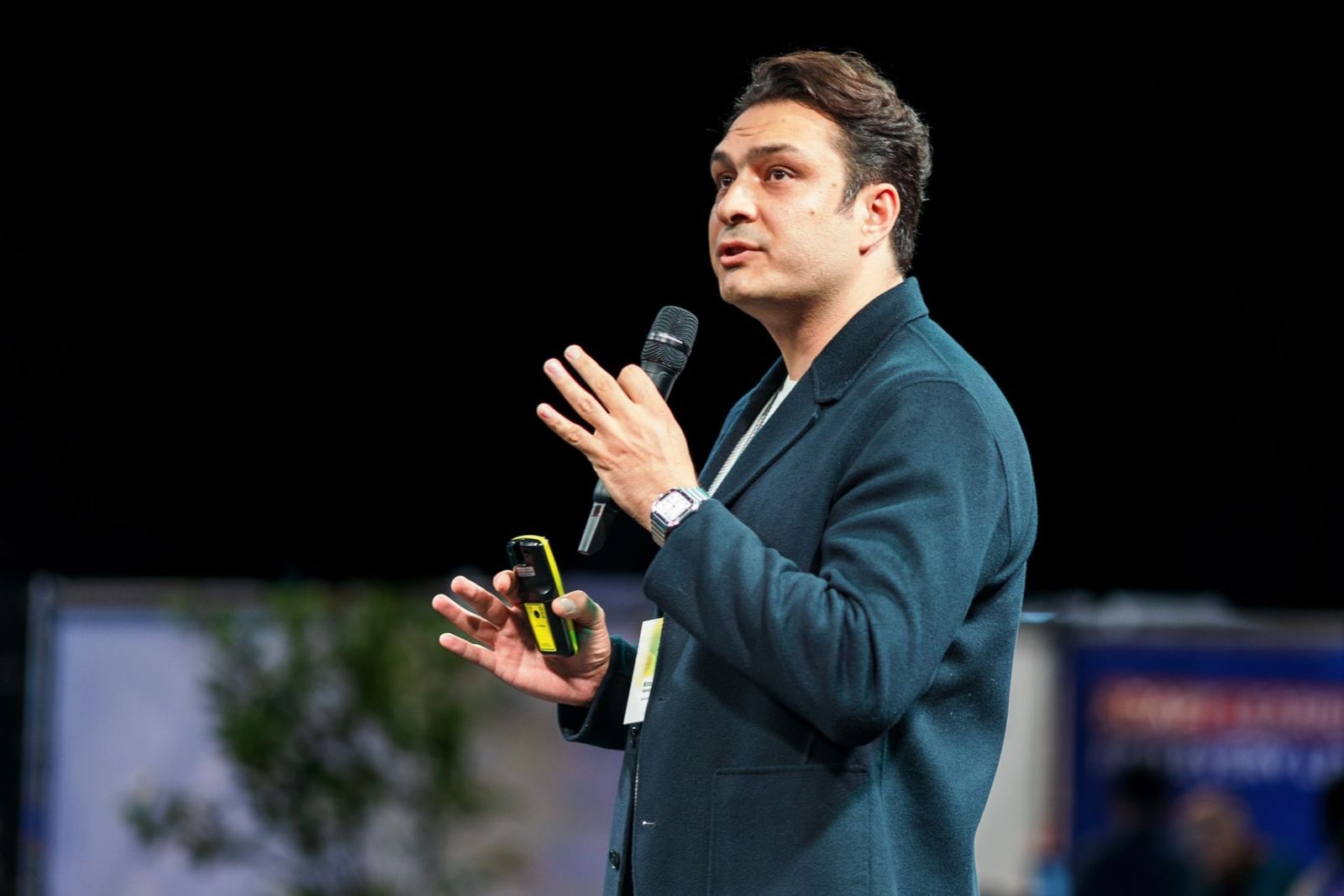 Nima Eskandari speaking on stage with a microphone