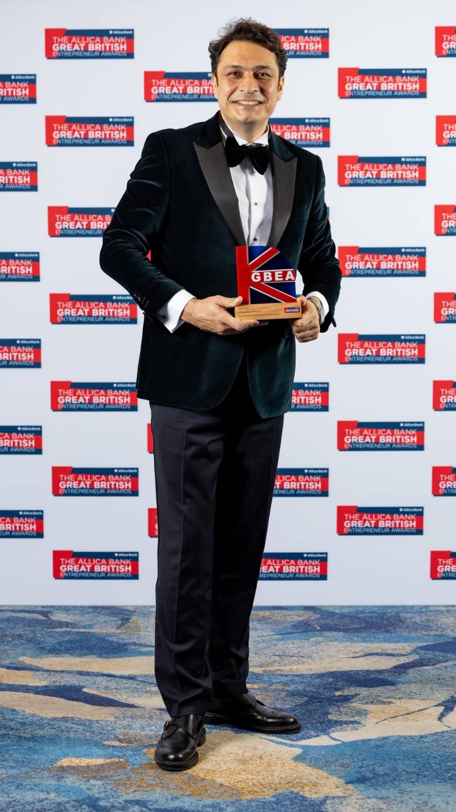Nima Eskandari holding a red GBEA trophy at the Great British Entrepreneur Awards