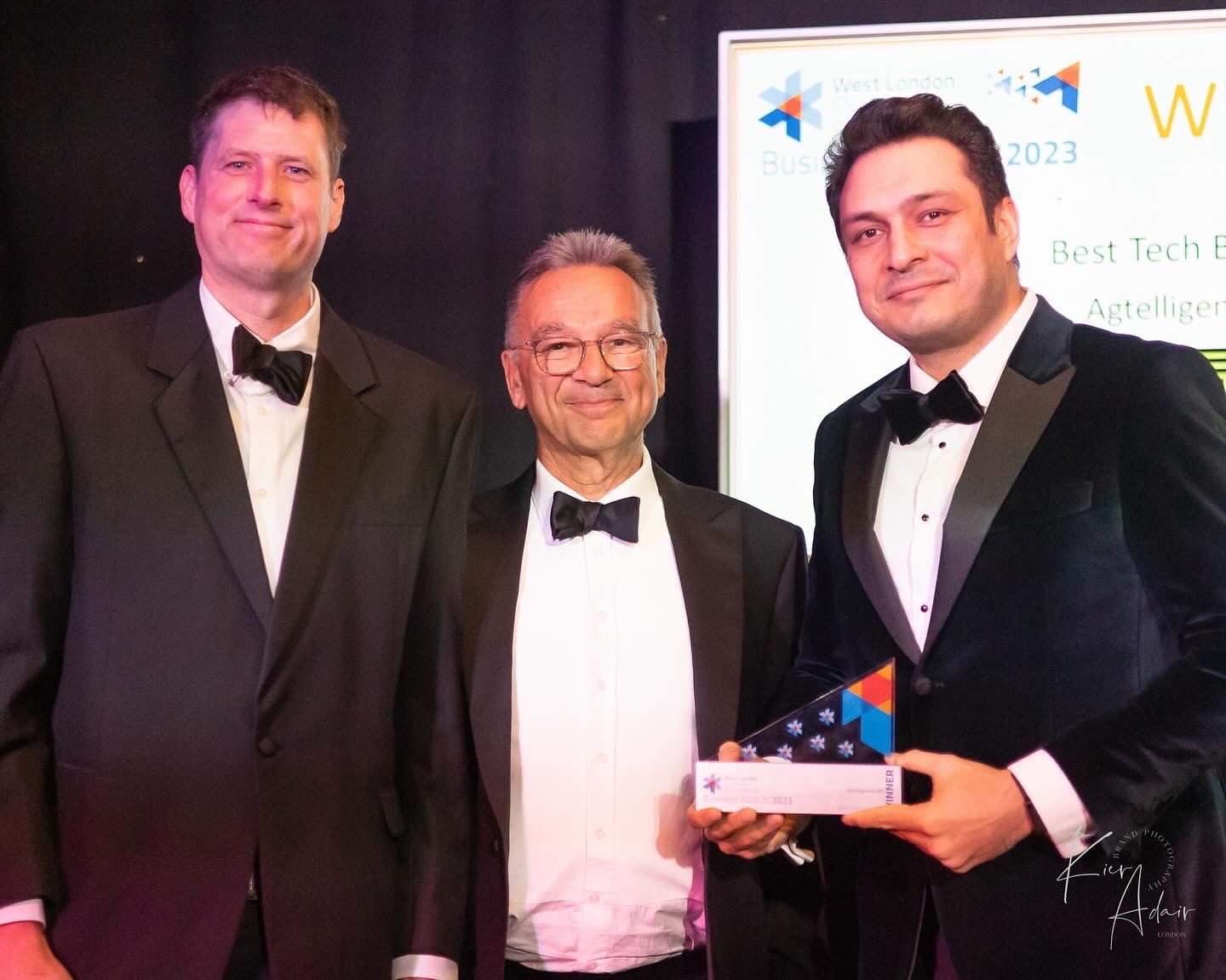 Three men in tuxedos at the West London Business Awards 2023, one holding the Best Tech Business award