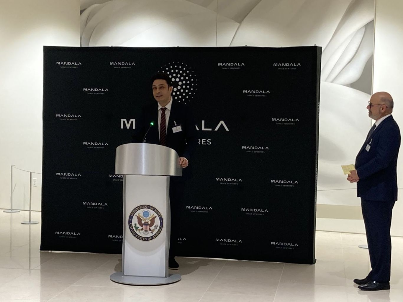 Nima Eskandari at a lectern bearing the seal of the United States Department of State, in front of a Mandala Space Ventures backdrop